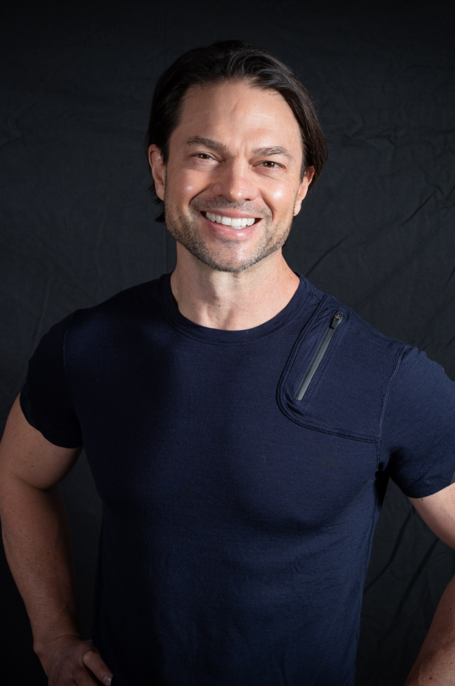 Image of John Montgomery smiling wearing blue fitted shirt
